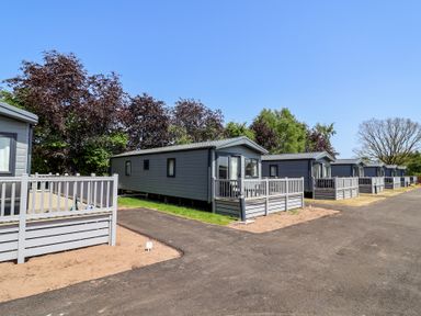 A row of mobile homes with decking in an outdoor area at Cedar Lodge 3 Bedrooms with hot tub Delamere