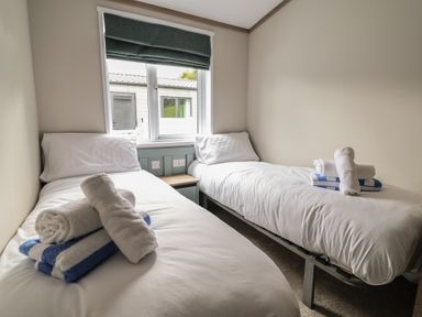 A bedroom with two single beds and towels at Cedar Lodge 3 Bedrooms with hot tub in Delamere