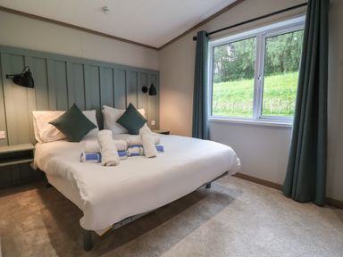 A bedroom with a bed and bedside lamps at Cedar Lodge 3 Bedrooms with hot tub, Delamere