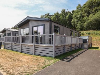 A log cabin with a decking area at Cedar Lodge 3 Bedrooms with hot tub Delamere