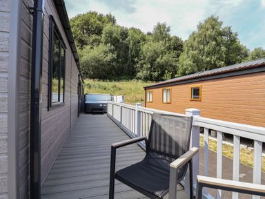 A deck with a hot tub and chair at Cedar Lodge 3 Bedrooms with hot tub in Delamere