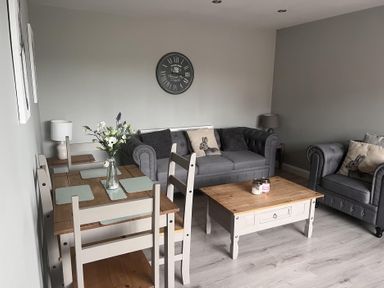 A living room with a table, chairs, and a sofa at 43 Goose Green Road in King's Lynn
