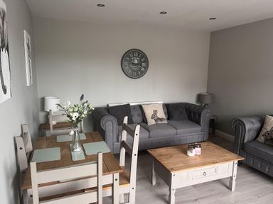 A living room with a sofa and dining table at 43 Goose Green Road in King's Lynn