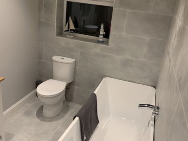 A bathroom with a tub and toilet at 43 Goose Green Road in King's Lynn