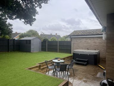 A garden with a table and chairs near a hot tub at 43 Goose Green Road in King's Lynn