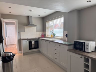 A kitchen with an oven, sink, microwave, and trash can at 15 Lamsey Lane in King's Lynn