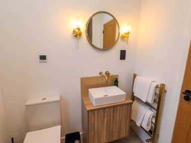A bathroom with a sink, toilet, and towels hanging at 1 Dairy Fields Longframlington