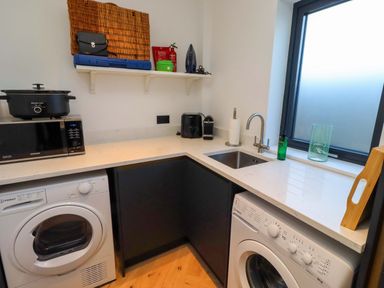 A laundry room with a washing machine, dryer, and countertop at 1 Dairy Fields, Longframlington