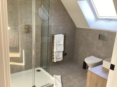A bathroom with a shower, toilet, towels, and sink at The Barn in Longframlington