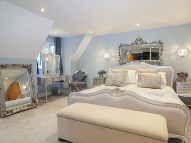 A bedroom with a bed and mirrors at Woodlands house in Ringwood