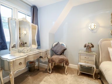 A bedroom with a vanity table and a chair at Woodlands house Ringwood