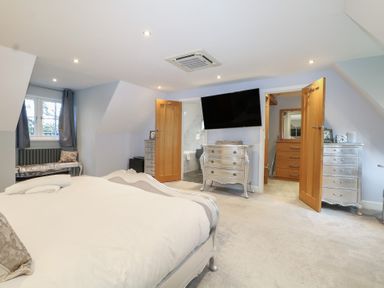 A bedroom with a television and dressers at Woodlands house in Ringwood