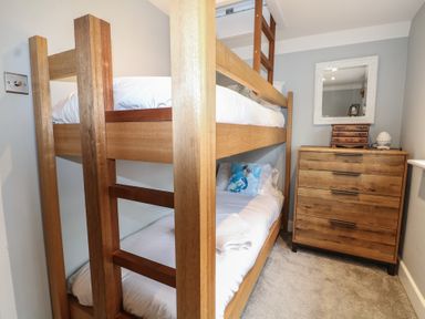 A bedroom with a bunk bed and a dresser at Woodlands house Ringwood