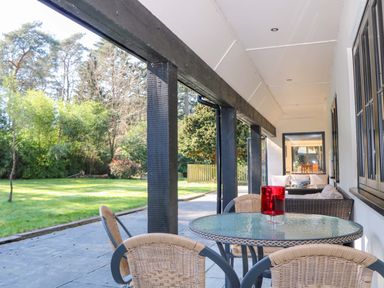 A patio area with a table and chairs overlooking the garden at Woodlands House in Ringwood
