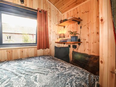 A bedroom with a bed and shelf at Dunfell Shepherd's Hut Appleby-In-Westmorland