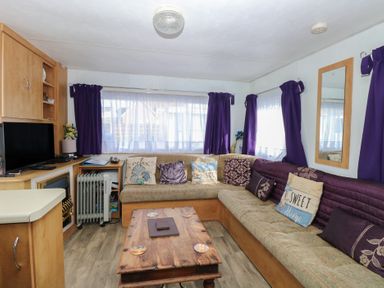 A living room with a sofa and coffee table at Whispering Meadows - 104 in Hemsby