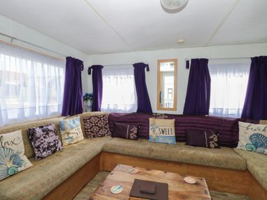 A living room with a sofa and coffee table at Whispering Meadows - 104, Hemsby