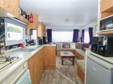 A kitchen and living area with a sofa and coffee table at Whispering Meadows - 104 Hemsby