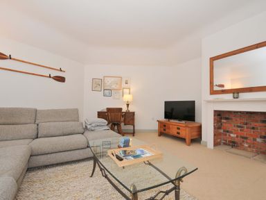 A living room with a sofa, table, and television at Cribba in Port Isaac
