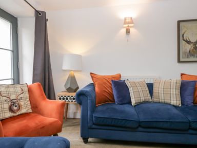A living room with a blue sofa and orange armchair at No.2 The Flags, Grange-over-Sands