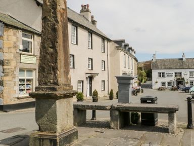 An outdoor scene featuring a street with buildings and a bench at No.2 The Flags, Grange-over-Sands