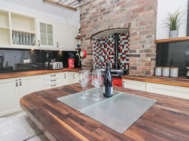 A kitchen with wine glasses and bottles on the counter at No.2 The Flags Cartmel