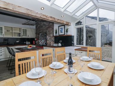 A dining room with a wooden table set for a meal at No.2 The Flags in Cartmel