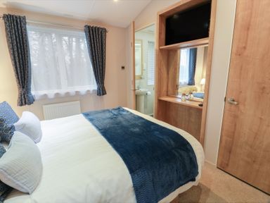A bedroom with a bed and a TV at Serenity Lodge in Wemyss Bay