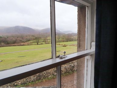 A window with a view of mountains and grass outside at Easthwaite Cottage in Holmrook near Easthwaite Farm