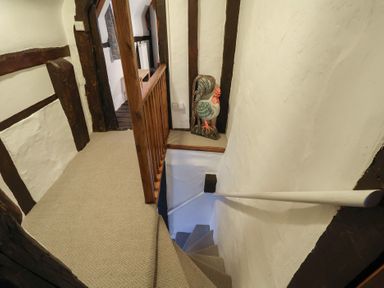 A staircase and a rooster decoration in the hallway at Driftway Cottage in Diss
