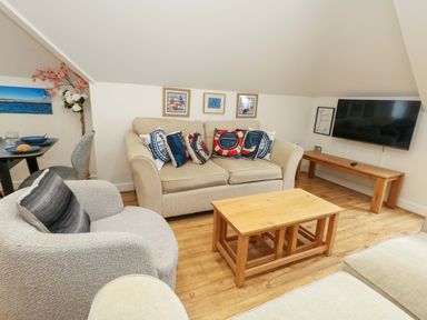 A living room with a sofa, coffee table, television and wall art at Flat 7 Weymouth
