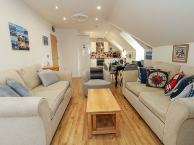 A living room with a sofa, coffee table and open kitchen at Flat 7 Weymouth