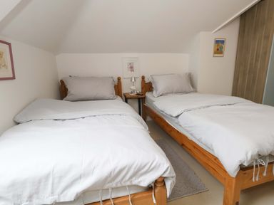 A bedroom with two beds and a side table at Flat 7 in Weymouth