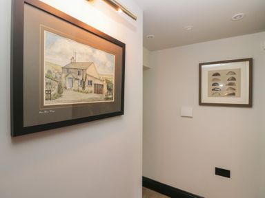 A hallway with framed pictures on the walls at Low House Cottage Ayside near Newby Bridge