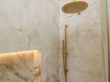 A shower with a rainfall shower head and marble wall panels at Low House Cottage Ayside near Newby Bridge