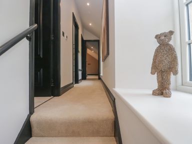 A hallway with a staircase and a bear figure at Low House Cottage Ayside near Newby Bridge