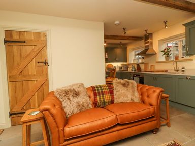 A kitchen with a sofa and wooden door at Bridge House Cottage Burn Bridge near Harrogate