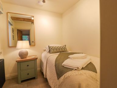 A bedroom with a single bed and a lamp at Bridge House Cottage in Burn Bridge near Harrogate
