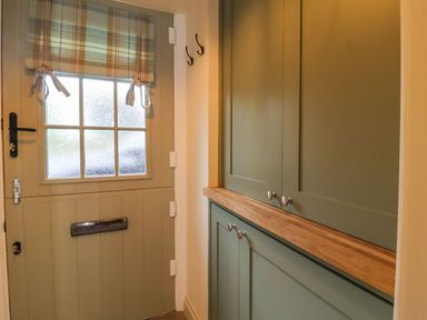 A hallway with a door and cabinet at Bridge House Cottage in Burn Bridge near Harrogate