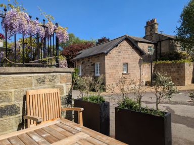 An outdoor area with a wooden table and chairs at Bridge House Cottage Burn Bridge near Harrogate