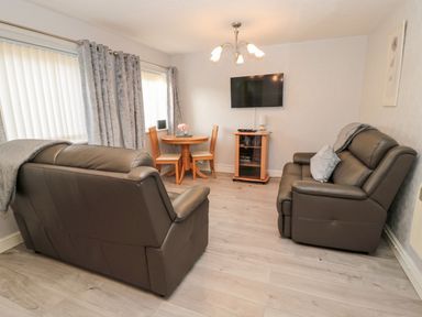 A living room with a sofa and a dining table at Primrose Cottage in Chathill