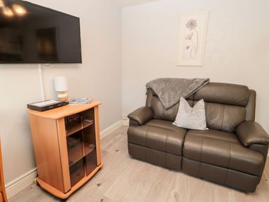 A living room with a sofa and television at Primrose Cottage in Chathill