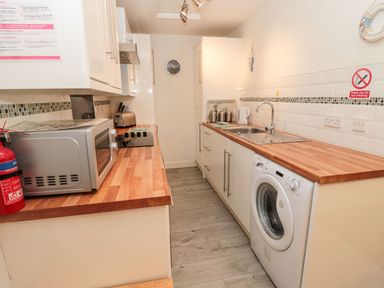 A kitchen with a washing machine and microwave at Primrose Cottage Chathill