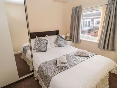 A bedroom with a double bed and a nightstand at Primrose Cottage in Chathill
