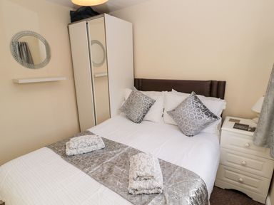 A bedroom with a bed and wardrobe at Primrose Cottage in Chathill