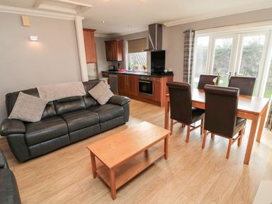 A living room with a sofa and dining area at Megstone in Chathill