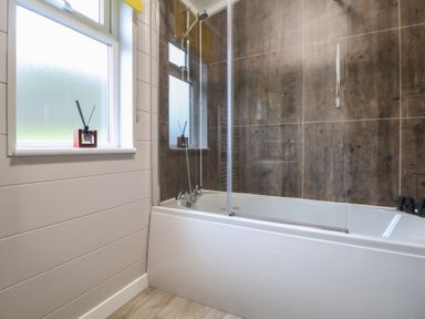 A bathroom with a bathtub and shower at Holly Lodge in Lloc near Caerwys