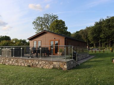 A cabin with a deck and hot tub at Holly Lodge near Lloc in Caerwys