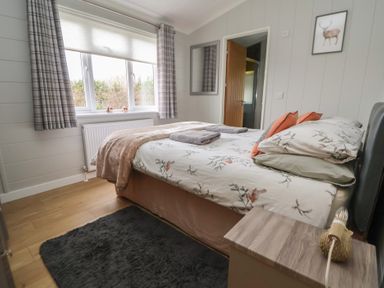 A bedroom with a bed and curtains at Pine Lodge in Lloc near Caerwys