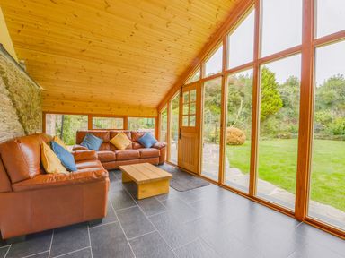 A conservatory with a sofa and coffee table at The Cider Barn at Home Farm Down Thomas near Wembury
